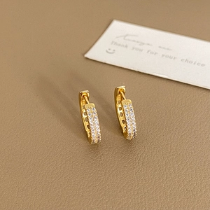 Boucles d'oreilles créoles dorées avec double rangée de zircons sur fond cuir