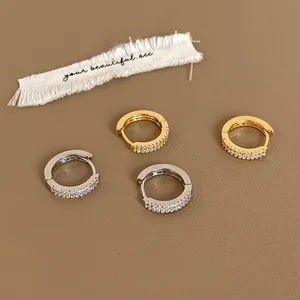Détail de créoles en or et argent avec sertissage micro-pavé de zircon à deux rangs