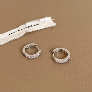 Vue macro de boucles d'oreilles créoles avec double rangée de zircons sur cuir texturé