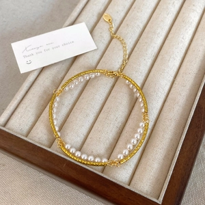 Detail of double-layer bracelet with 18K gold chain, pearls and branded logo pendant