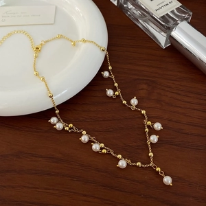 Elegant gold-plated freshwater pearl tassel necklace displayed on a dark wooden background