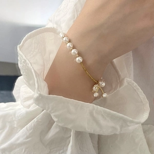 Elegant cherry pendant bracelet with white pearls and gold chain on female wrist
