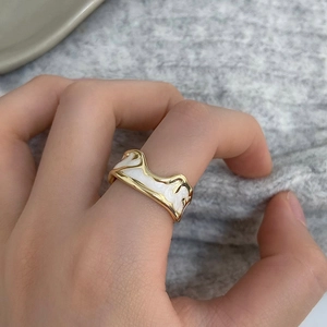 Close-up of vintage enamel wave ring in gold and white on model's finger