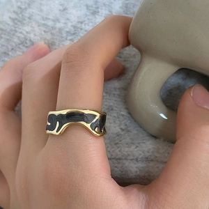 Detail of vintage enamel ring with marble pattern worn by hand against home decor