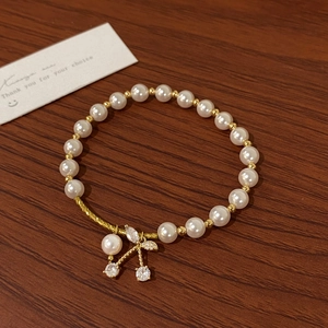 Detailed macro view of an elegant pearl bracelet with a golden zircon cherry blossom pendant