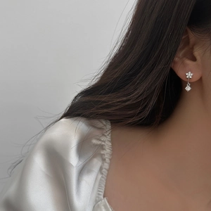 Elegante silberne Blumenohrringe mit funkelndem Zirkonia-Tropfen am Model-Nahaufnahme