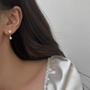 Elegante silberne Blumenohrringe mit funkelnden Zirkonia, Nahaufnahme an einem Model