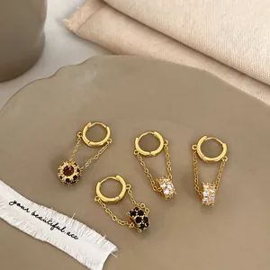 Detail of gold-plated hoop earrings with cubic zirconia charms on a ceramic tray