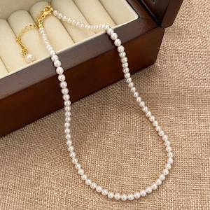 Detail of round cream pearl necklace with gold clasp on wooden jewelry box