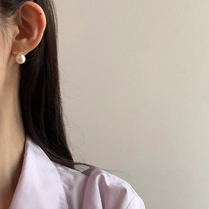 Close-up of a minimalist pearl earring with a sleek silver bar on a model's ear