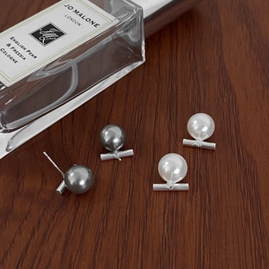Chic horizontal silver bar stud earrings with white and grey pearls on a wooden surface