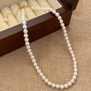 Detailed macro view of white round pearls with a gold lobster clasp on a vintage wood box