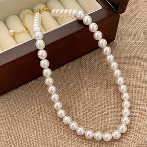 Detailed macro of round white pearls with golden clasp on vintage wooden jewelry box