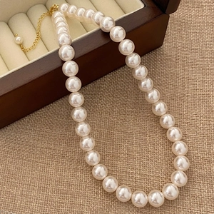 Detailed shot of cream pearl necklace with gold extender chain on a vintage jewelry box