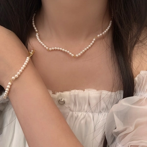 Close-up of elegant white pearl necklace and bracelet set with gold-plated clasps on model