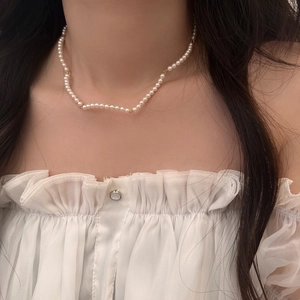 Elegant white pearl necklace with gold plated clasp worn on a lace blouse