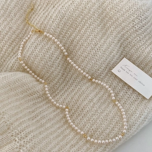 Detail of white pearls and gold-plated chain link necklace on soft knit fabric