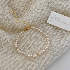 Detail of elegant micro pearl bracelet with adjustable gold plated lobster clasp on knit