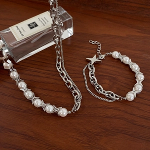 Silver star and pearl chain necklace and bracelet set on a dark wooden surface