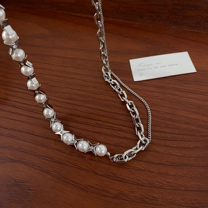 Detail of star-shaped pearl setting and silver chain necklace on dark wood surface