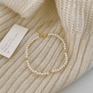Detail of beaded pearl bracelet with gold spacers on soft knit fabric background