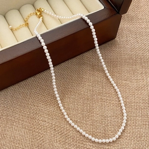 Close-up of pearl necklace with gold lobster clasp and adjustable chain in a jewelry box