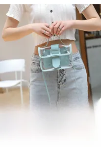 Transparent mini PVC crossbody bag with light blue leather trim shown in a handheld view