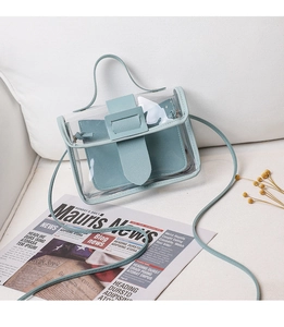 Detail of mint blue transparent PVC mini crossbody bag on white sofa with dry flowers
