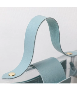 Detail of light blue textured handle with gold rivets on transparent PVC tote bag