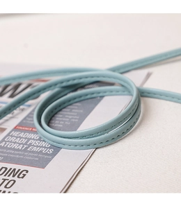 Close-up of light blue leather strap with precision stitching on a newspaper background