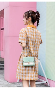 Detail of light green and beige contrast crossbody bag with gold chain and metal lock