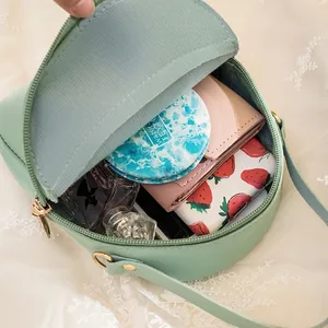 Green mini crossbody bag showing internal storage for wallet, mirror and perfume