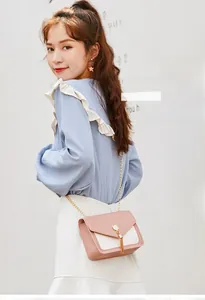Pink and white crossbody bag with cat buckle and chain strap shown on model