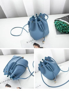 Detail view of blue pebbled leather bucket bag showing drawstring and gold hardware