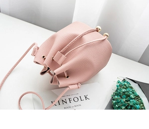 Detail of pink pebbled leather bucket bag with gold bead accents and drawstring closure