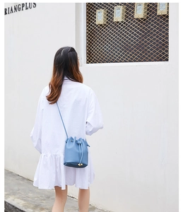 Detail of blue pebbled leather bucket bag with drawstring and gold metal hardware accents