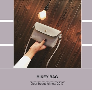 Detail of light gray lychee grain leather crossbody bag with gold bead snap and thin strap