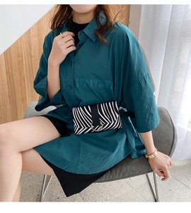Close-up of zebra pattern mini waist bag with golden ring on blue oversized shirt