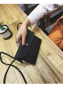 Detail of black lychee texture PU leather small square bag with golden buckle closure