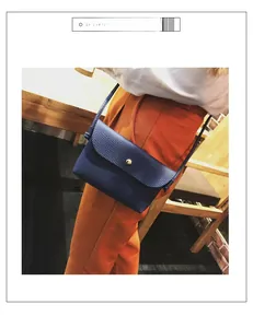 Detail of navy blue pebble leather crossbody bag with a round gold buckle on orange trousers