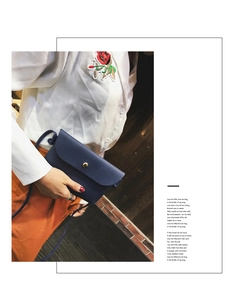 Detail view of a small dark blue crossbody bag with lychee texture and gold button