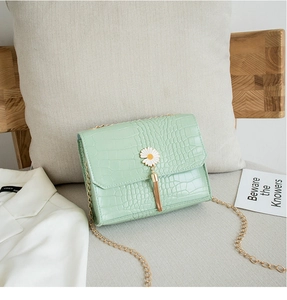 Dettaglio borsa verde chiaro effetto coccodrillo con decoro margherita e catena d'oro