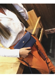 Detail of dark blue lychee grain leather crossbody bag with elegant gold metal buckle