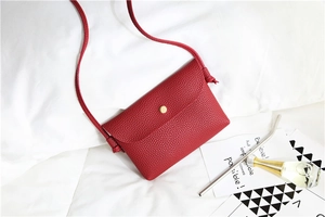 Close-up of red pebbled leather mini crossbody bag with minimalist gold metal snap button
