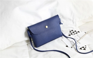 Detail shot of navy blue lychee grain leather crossbody bag with gold metal buckle