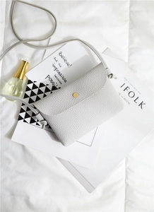 Close-up of light gray pebble leather small square bag with golden magnetic clasp
