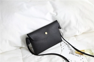 Detail of black crossbody bag featuring lychee texture and gold magnetic closure