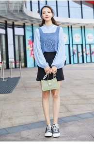 Borsa verde chiaro a coccodrillo con catena bianca abbinata a gilet in maglia blu e gonna