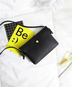 Close-up of black litchi pattern mini crossbody bag with a round gold snap fastener