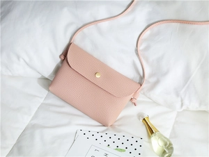 Detail of pink pebbled PU leather crossbody bag with golden magnetic snap and thin strap